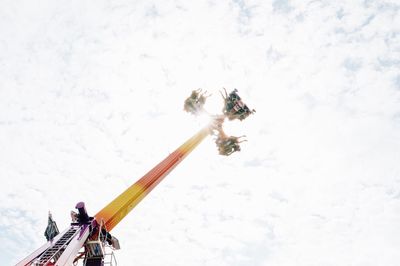 Low angle view of people skiing on snow against sky