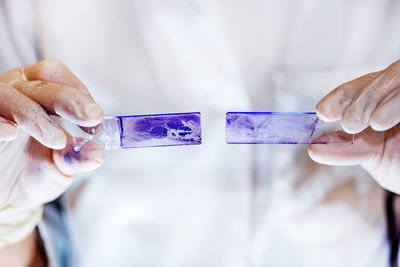 Midsection of scientist examining chemical on slide in laboratory