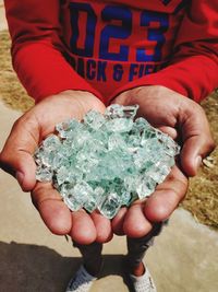 Midsection of man holding crystals in cupped hands outdoors