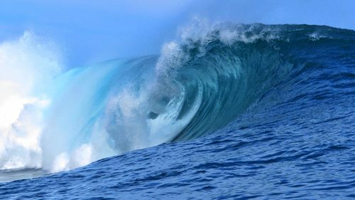 Scenic view of sea waves splashing against blue sky