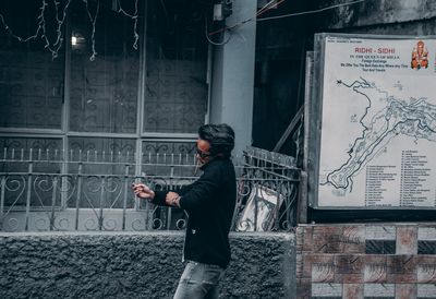 Side view of man standing against wall