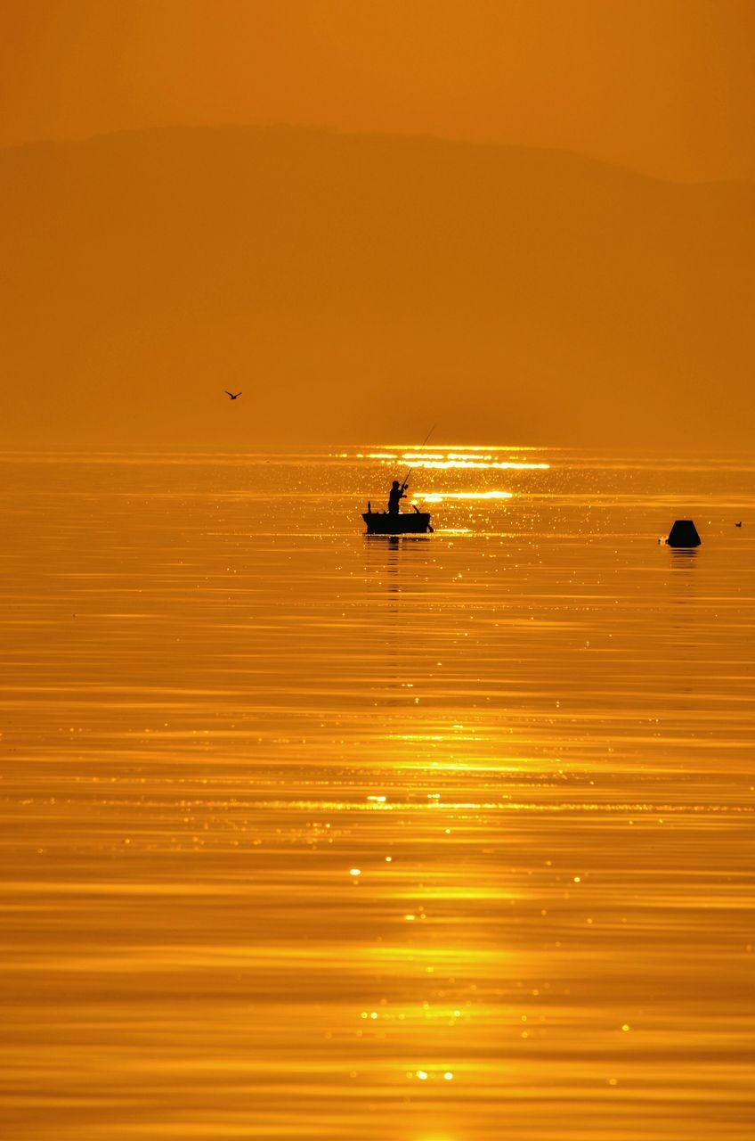 orange color, sunset, waterfront, water, reflection, silhouette, nature, leisure activity, unrecognizable person, outdoors, men, full length, lifestyles, transportation, beauty in nature, yellow, motion, sport