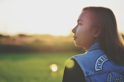 Side view of young woman looking away against sky