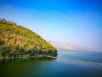 Scenic view of lake and mountains against clear blue sky