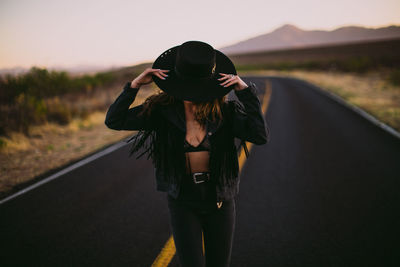 Woman in black hat and fringe dancing the street at sunset