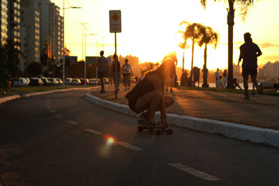 People walking on road at sunset