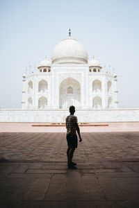 Rear view of woman standing in front of historical building