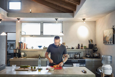 Man cutting vegetable at kitchen counter