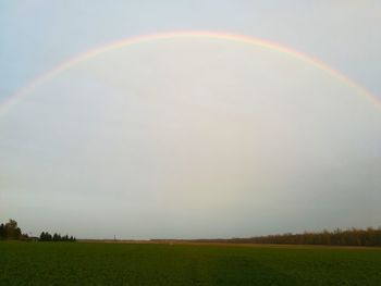 Scenic view of field against rainbow in sky