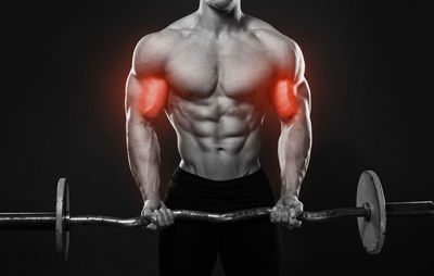 Low section of shirtless man exercising in gym