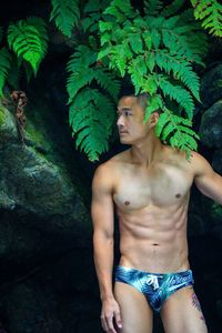 Midsection of young man standing against plants