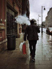 Rear view of man walking on street in city