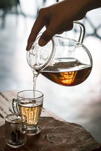 Close-up of hand pouring drink in glass