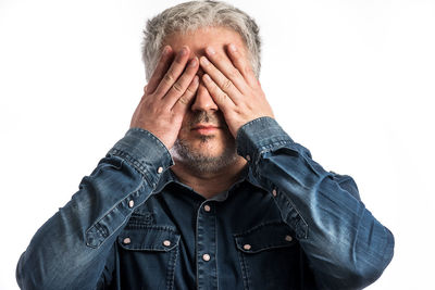 Portrait of man covering face against white background