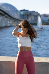 Beautiful woman exercising while standing by bay