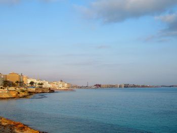 Scenic view of sea by buildings against sky
