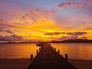 Pier over sea against orange sky