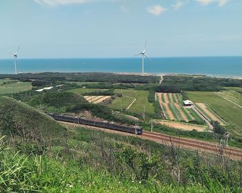 Scenic view of agricultural field by sea against sky