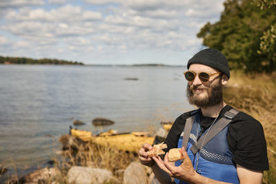 Smiling man at lake wearing jacket and holding food