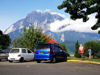Women standing by parked cars against mountain