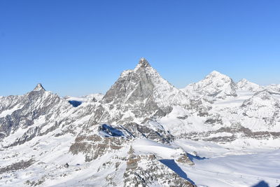 Scenic view of snowcapped mountains against clear blue sky