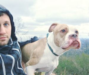Portrait of man with pit bull terrier against sky