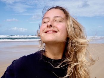 Portrait of beautiful woman on beach against sky