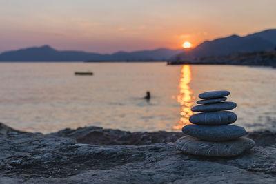 Stack of stones in sea during sunset
