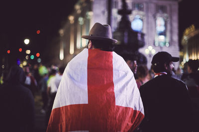 Rear view of person draped in england flag at night