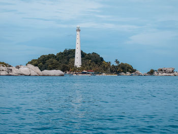 Lighthouse by sea against sky