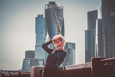 Portrait of woman standing against modern buildings in city