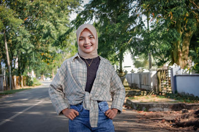 Portrait of teenage girl standing against trees