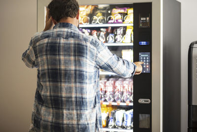 Rear view of man using vending machine