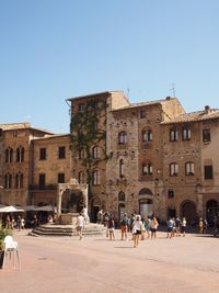 People in front of historical building against blue sky