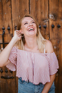 Blonde woman laughing out loud and touching her hair