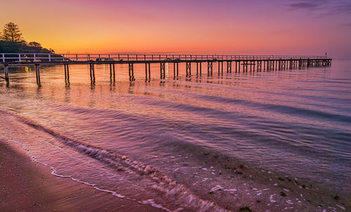 Pier over sea against sky during sunset