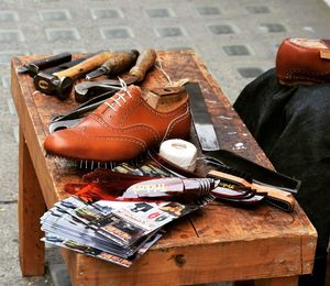 Midsection of cobbler with shoes by table on footpath