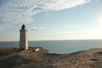 Lighthouse on beach against sky