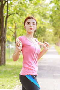 Young woman listening to music on headphones while standing outdoors