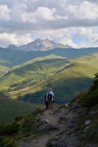 Rear view of people walking on mountain against sky