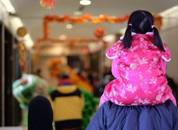 Rear view of young girl on person's shoulders