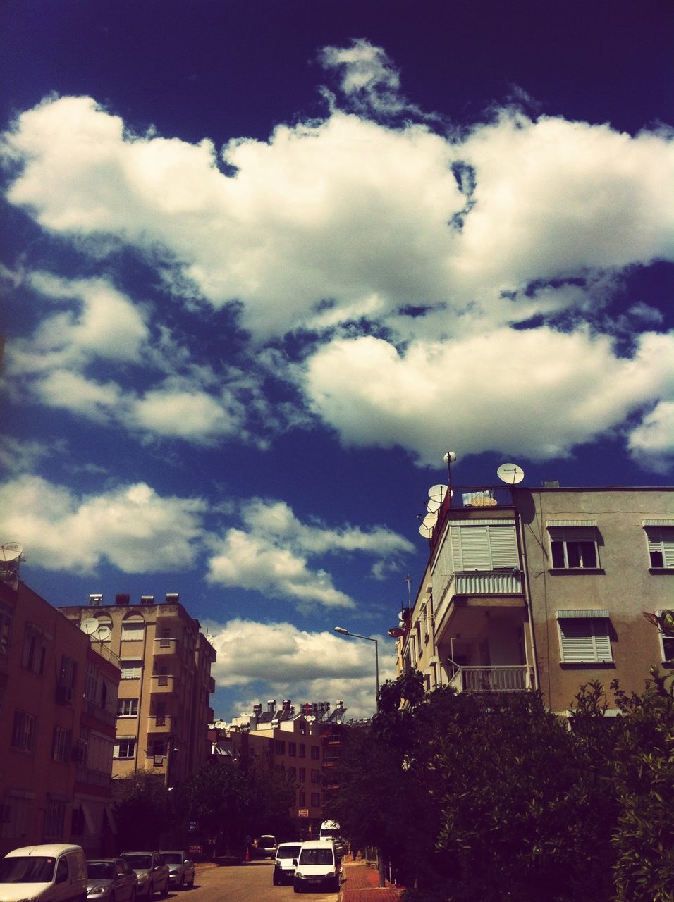 building exterior, car, architecture, transportation, built structure, land vehicle, mode of transport, sky, cloud - sky, street, city, cloudy, road, low angle view, cloud, building, street light, residential building, city street, outdoors