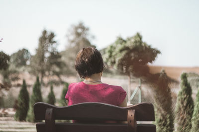 Rear view of woman sitting on bench