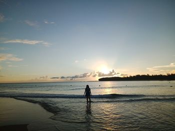 Silhouette man standing on beach against sky during sunset