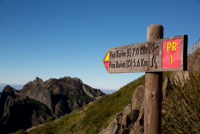 Close-up of signboard against clear blue sky