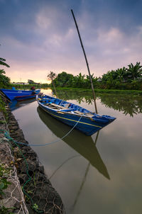 Boats moored in lake against sky