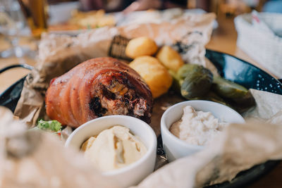 Baked pork shank served with baked potatoes, horseradish, mustard and pickled cucumbers. 