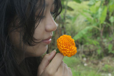Close-up of woman holding yellow marigold flower