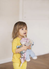 Portrait of cute girl with stuffed toy against wall