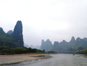 Scenic view of river by mountains against clear sky